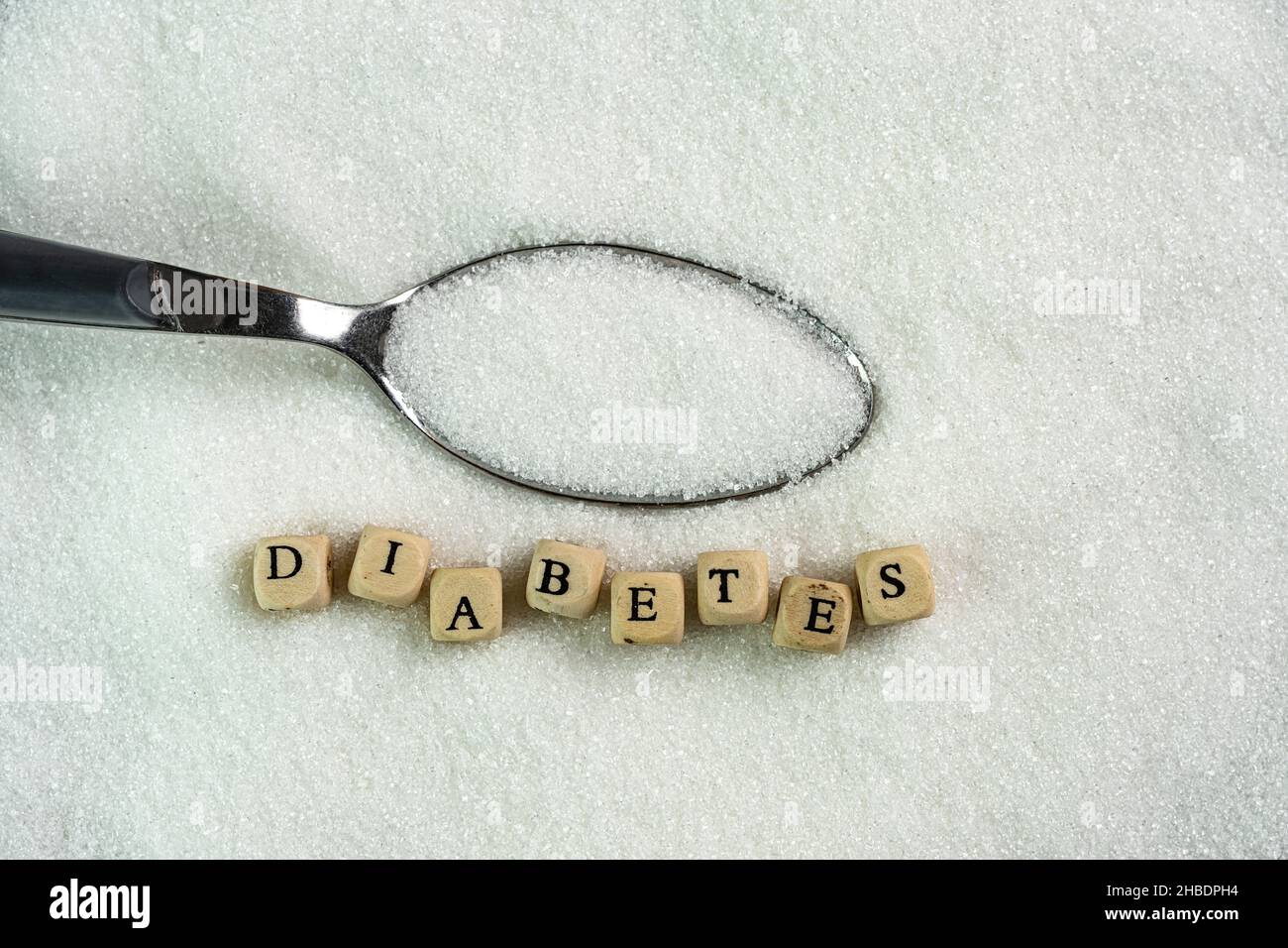 La parola diabete e un cucchiaio pieno di zucchero Foto Stock