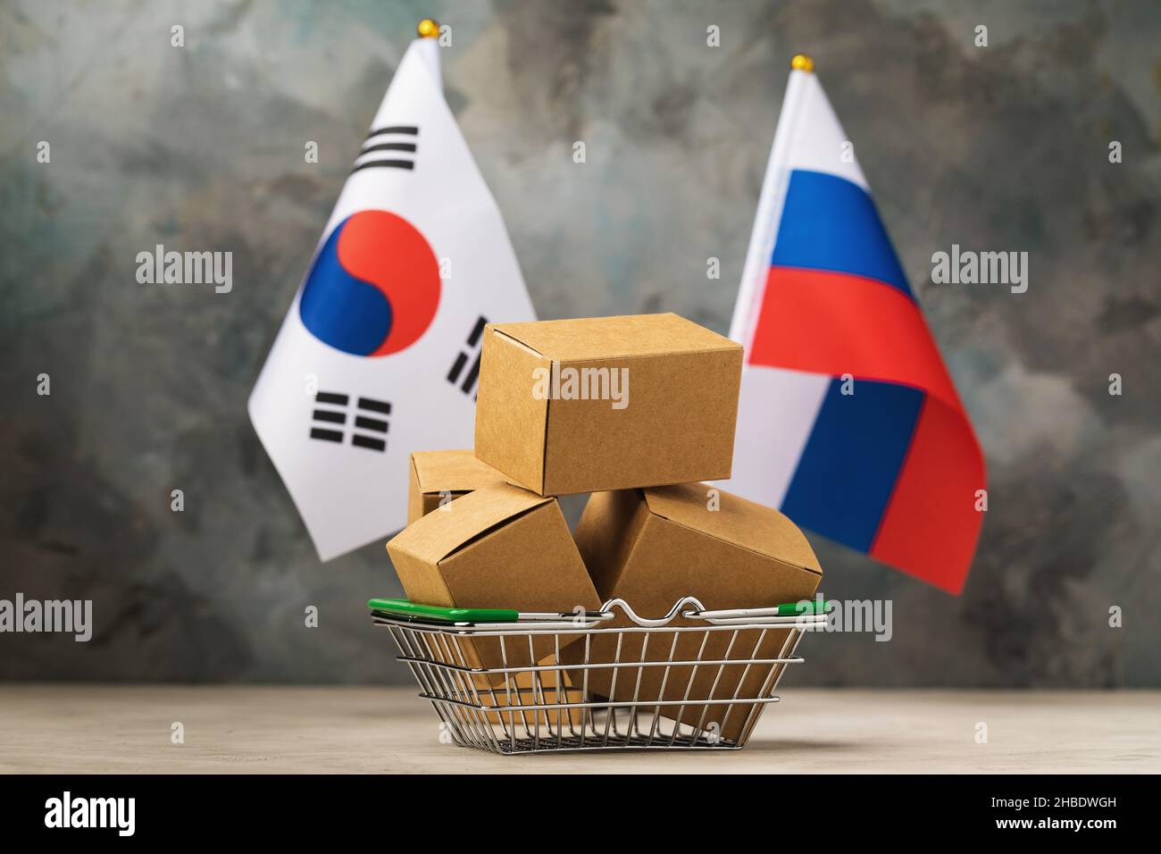 Cestino di cibo pieno di scatole, bandiere di Russia e Corea del Sud su un background astratto, il concetto di commercio tra Corea del Sud e Russia Foto Stock