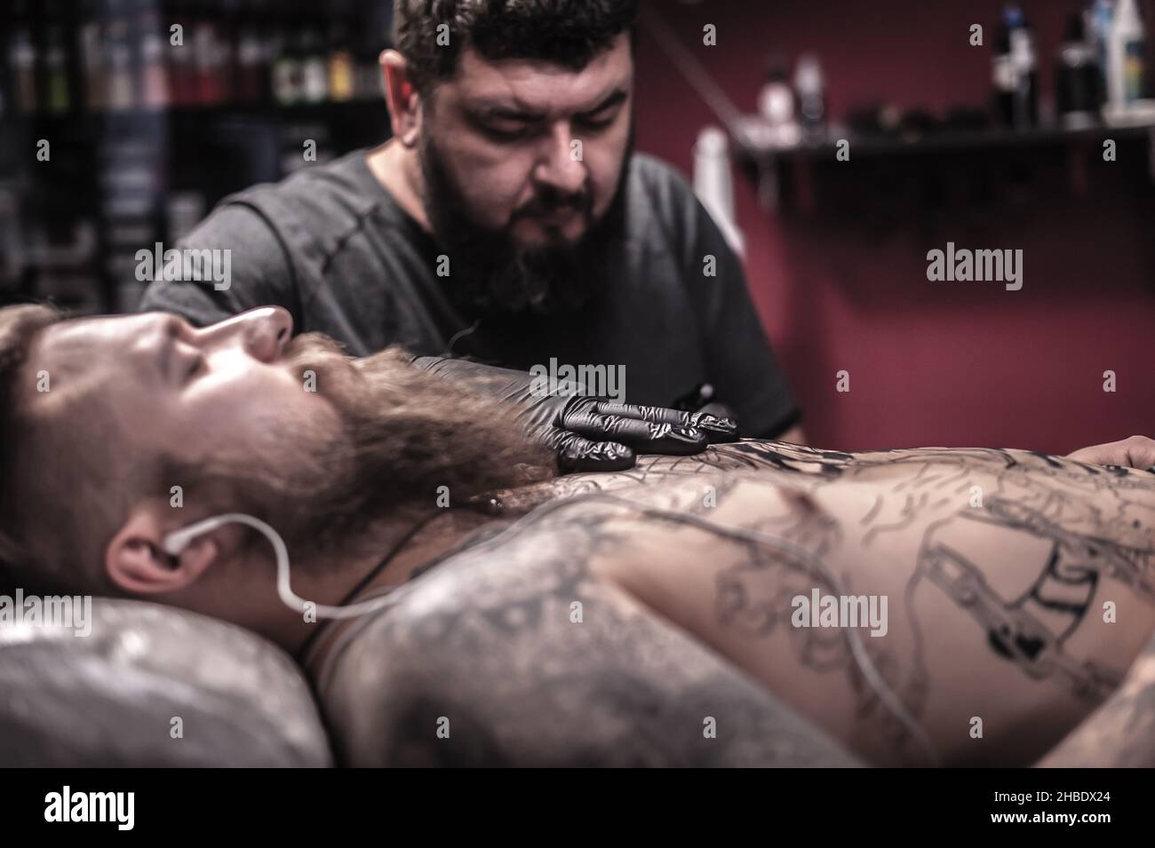 Il maestro dell'arte del tatuaggio dimostra il processo di ottenere il tatuaggio nel salone Foto Stock