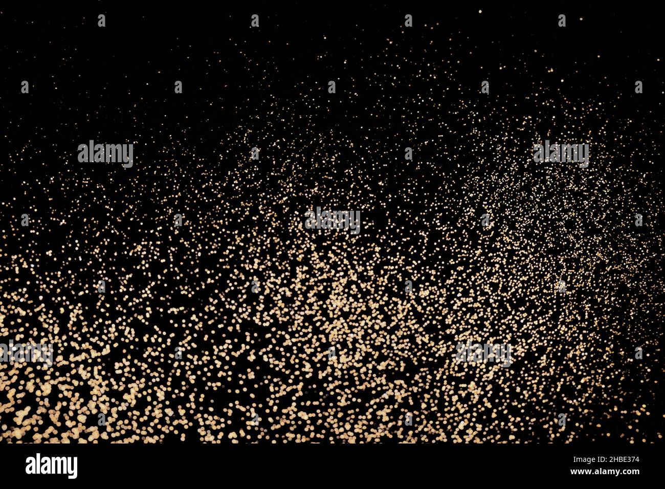 Sfondo nero festivo di luci dorate con glitter. Sfondo delle vacanze, focus selettivo Foto Stock