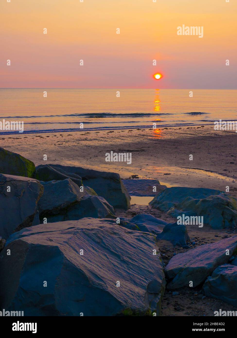 Tramonto sulle rocce sulla spiaggia a Tywyn. Una piccola località balneare sulla costa Cardigan Bay del sud di Gwynedd, Galles Foto Stock