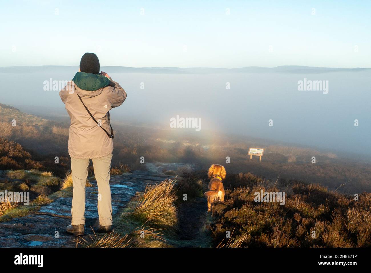 Ilkley, Yorkshire UK, 19 Dicembre 2021 - cane Walker fotografando un avvistamento raro di uno specter di brocken su Ilkley Moor (lo specter di brocken è il fotografo - si vede solo la propria - domanda è il cane ha uno?!). Credit: Rebecca Cole/Alamy Live News Foto Stock