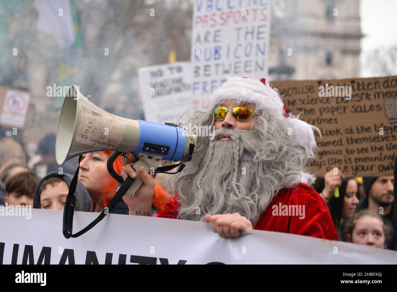 Un protester vestito come Santa tiene un megafono durante la manifestazione. I manifestanti anti anti anti anti-vaccino e anti-vaccino passano Uniti dagli oppositori delle restrizioni di Covid 19, si sono riuniti a Parliament Square e hanno marciato attraverso il centro di Londra. Foto Stock
