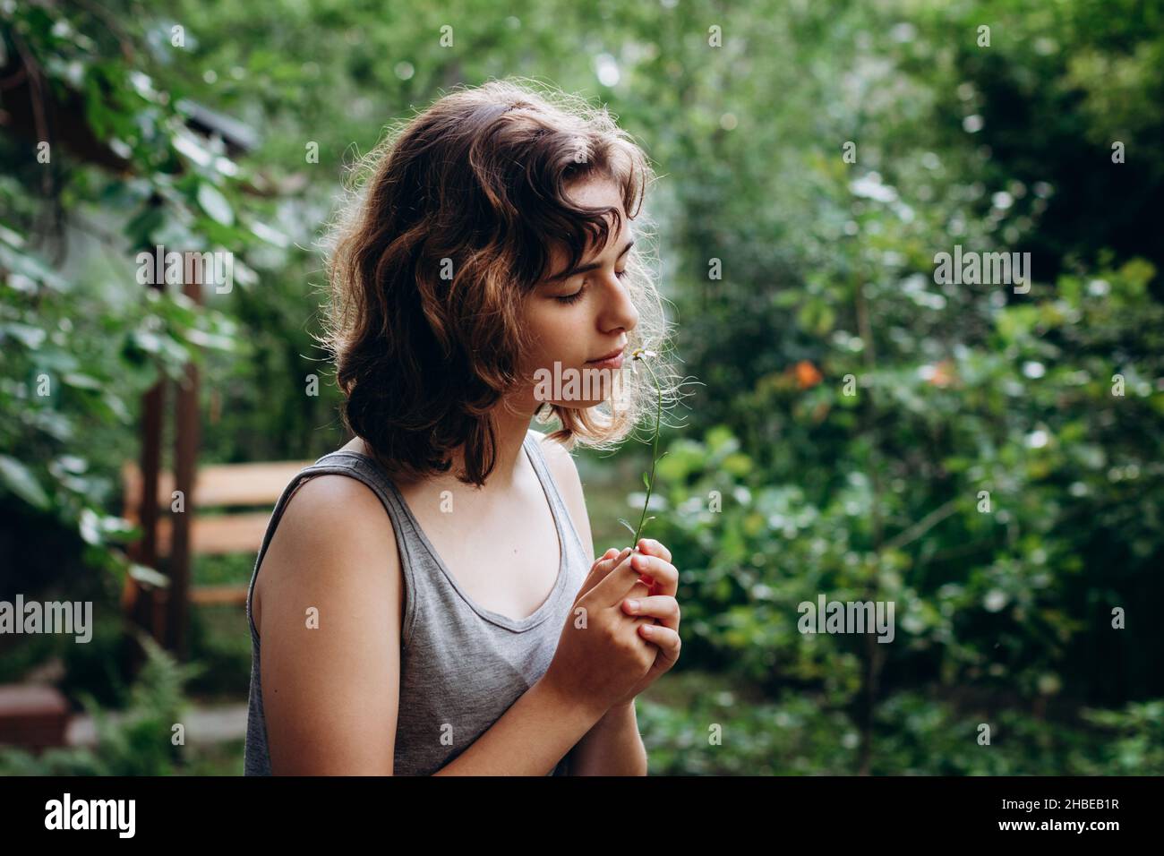 Ragazza teenager sniffing fiore camomilla ai boschi. Bellezza naturale. Momenti candidi Foto Stock