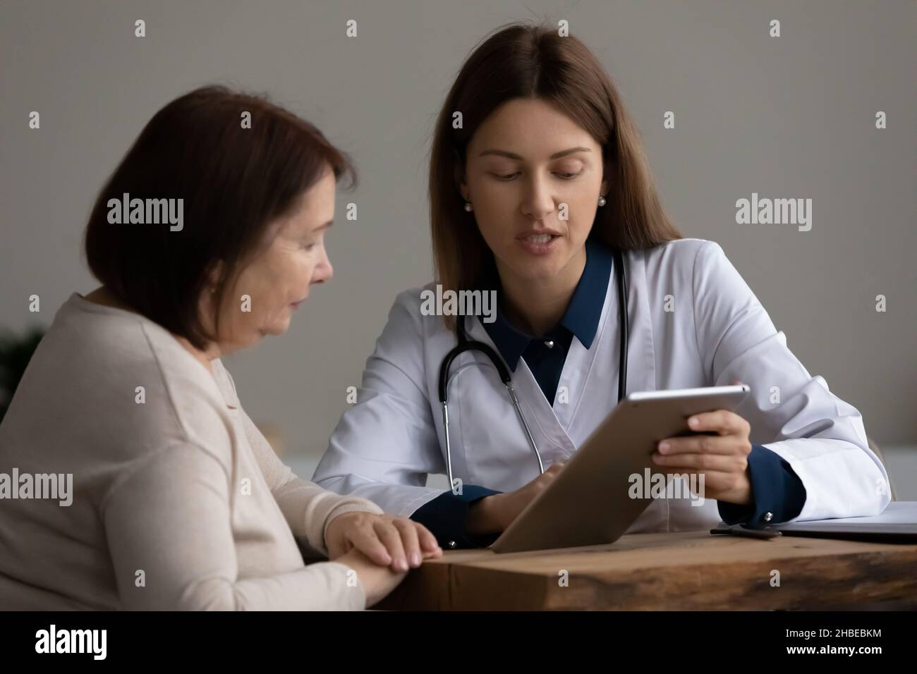 Il medico femminile mostra il risultato del test sul PC tablet al paziente Foto Stock