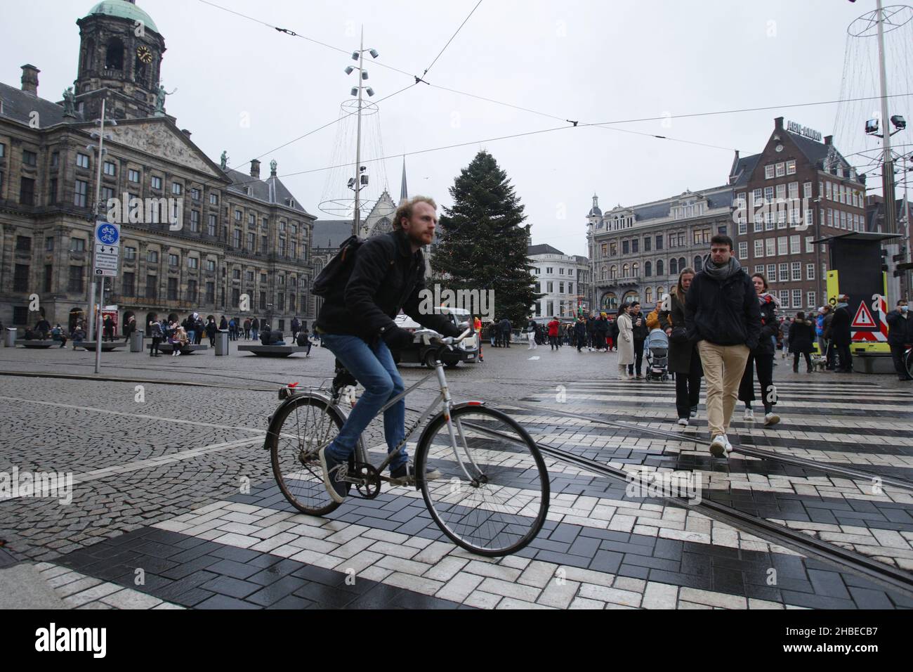 Amsterdam, Paesi Bassi. 19th Dic 2021. Un giro in ciclista passa per pedoni attraverso la zebra in piazza Dam tra la pandemia del coronavirus il 19 dicembre 2021 ad Amsterdam, Paesi Bassi. Il governo olandese ha imposto nuove misure per frenare la nuova variante Omicron, la chiusura di tutti i negozi tranne i più essenziali, così come ristoranti, parrucchieri, palestre, musei e altri luoghi pubblici da oggi ad almeno gennaio 14. (Foto di Paulo Amorim/Sipa USA) Credit: Sipa USA/Alamy Live News Foto Stock