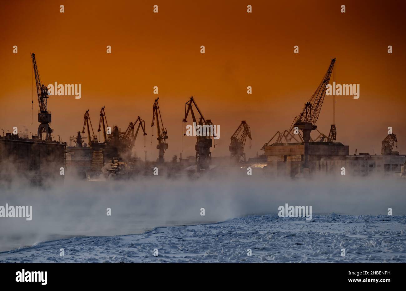 La costruzione di rompighiaccio nucleare al tramonto magico, gru del cantiere Baltico in una gelida giornata invernale, vapore sul fiume Neva, liscio Foto Stock