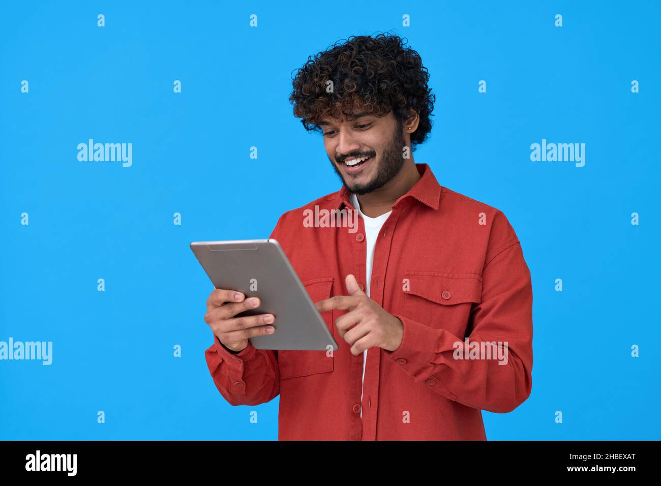 Ragazzo indiano felice utilizzando tablet digitale isolato su sfondo blu. Foto Stock