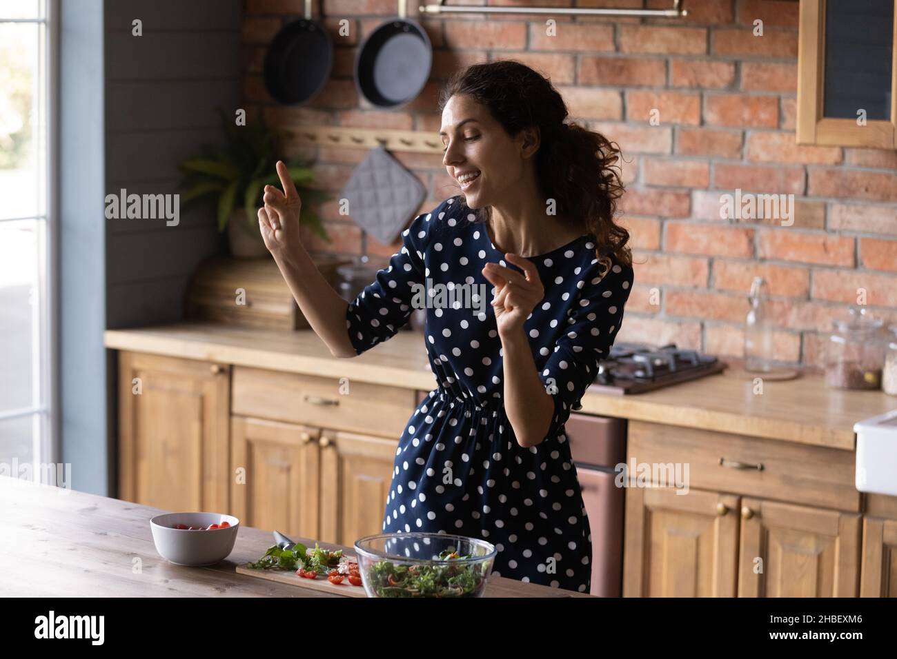 Gioiosa giovane ispanica che balla preparando il cibo a casa. Foto Stock