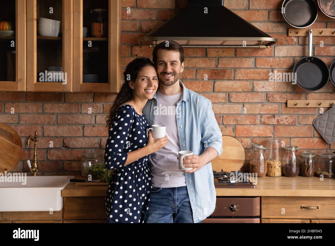 Ritratto di legame millennial amorevole coppia di famiglia in posa in cucina. Foto Stock