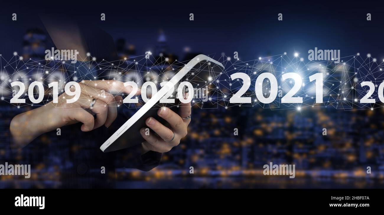 Anno nuovo 2021, obiettivo, piano, azione. Mano toccare tablet bianco con ologramma digitale 2021 segno sulla città scuro sfondo sfocato Foto Stock