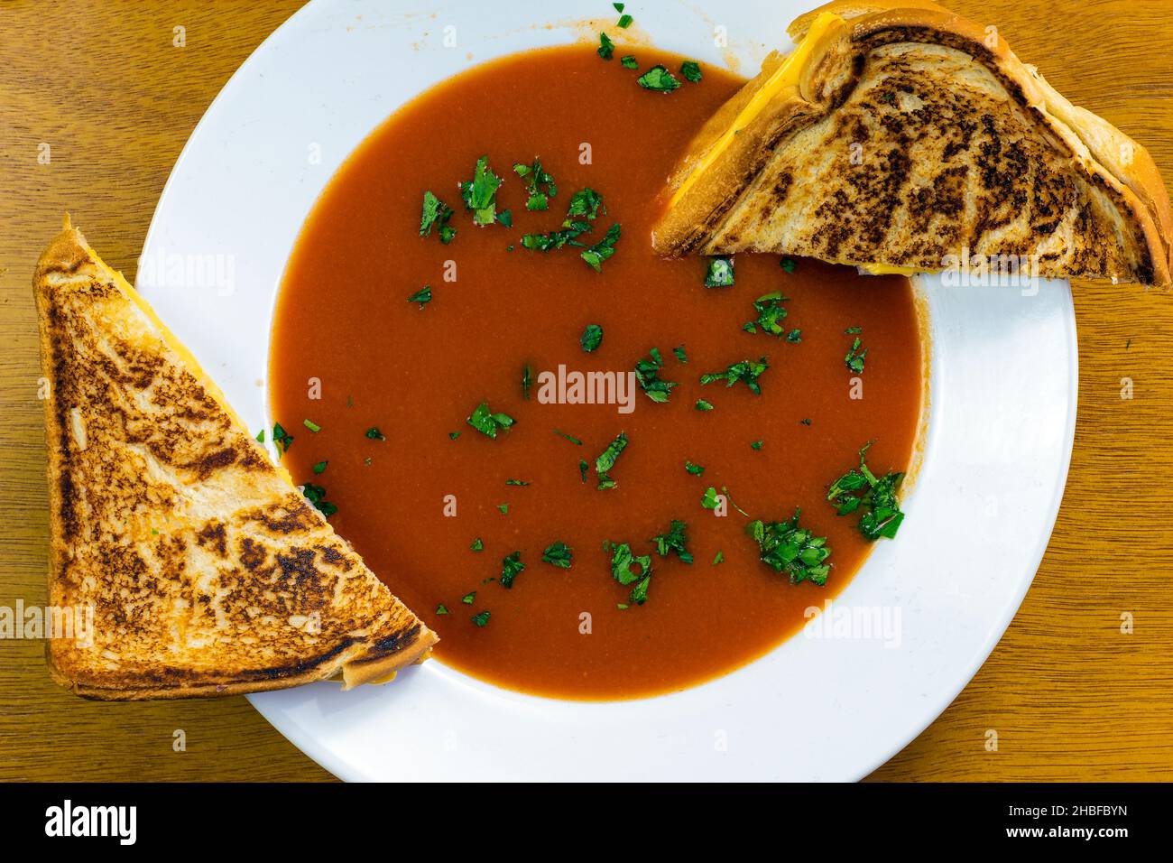 zuppa di pomodoro con prezzemolo e servito con un sandwich fuso al formaggio Foto Stock
