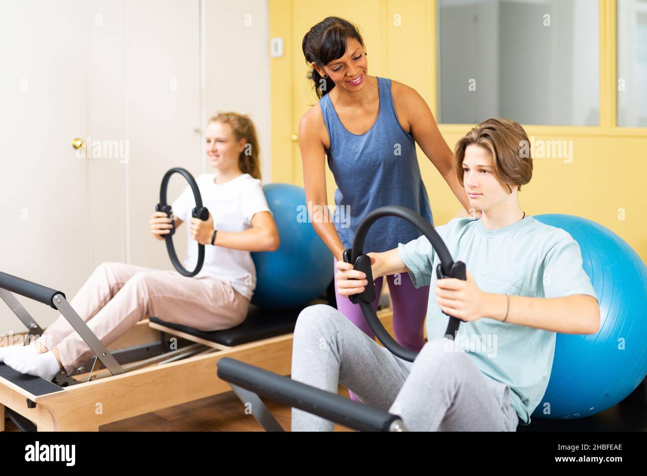 Gli adolescenti eseguono le esercitazioni con un anello di ginnastica sotto la guida del formatore Foto Stock Gli adolescenti eseguono le esercitazioni con un anello di ginnastica sotto la guida del formatore Foto Stock