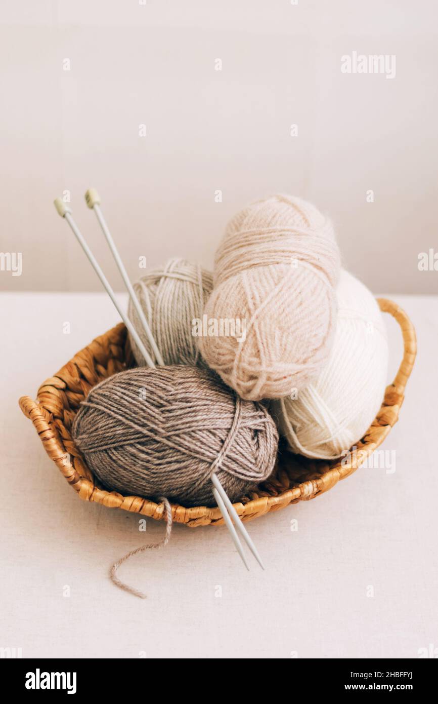 Lana naturale in palle di vari colori pastello in un cestino di vimini. I thread di Unione si avvicinano su uno sfondo chiaro. Foto Stock