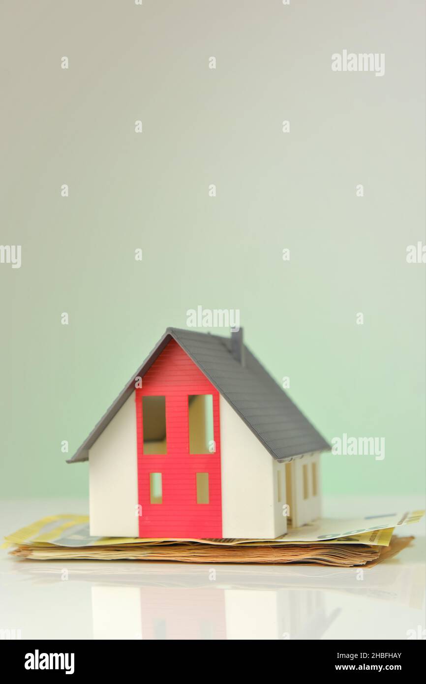 Casa e soldi. Casa mock con tetto su sfondo banconote in euro. Mercato immobiliare. Prestito immobiliare. Acquisto e costruzione di una casa. Foto Stock