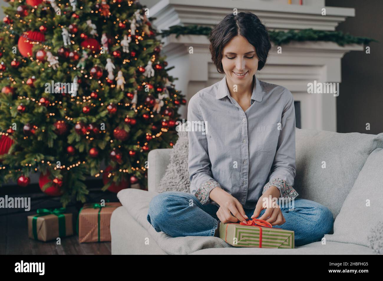 Buona donna italiana che si prepara per Natale a casa, confezionando e confezionando il regalo di natale Foto Stock