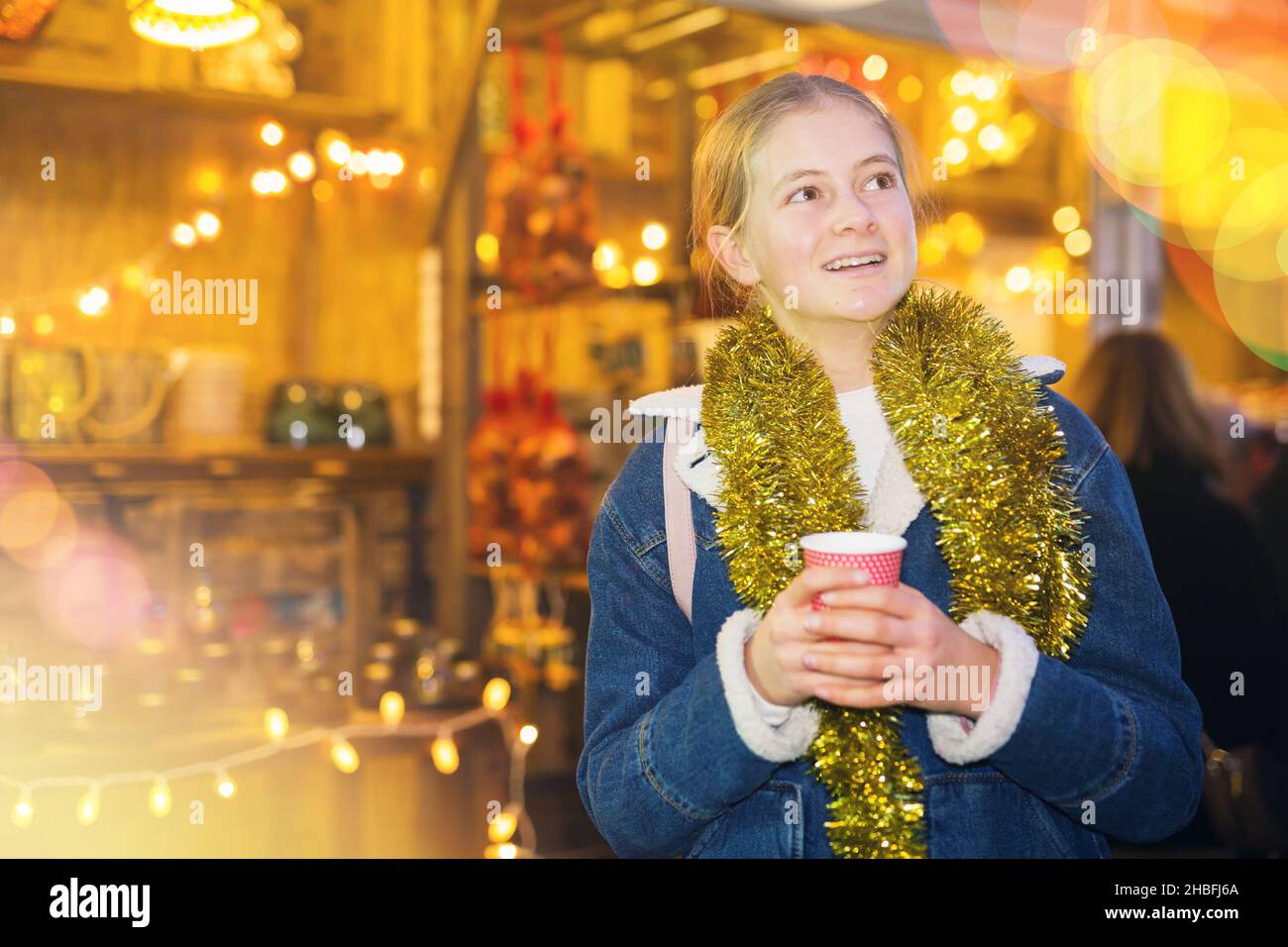 Adolescente ragazza che tiene la tazza calda di caffè nelle mani alla fiera di natale di strada Foto Stock