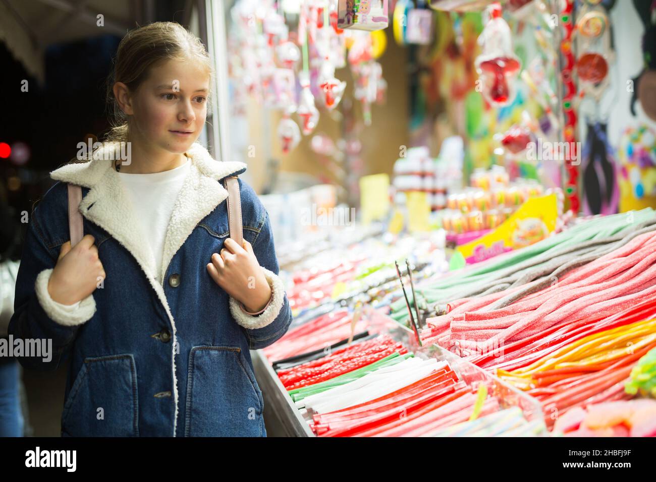 Ragazza adolescente che sceglie i dolci di Natale alla fiera di strada in serata Foto Stock
