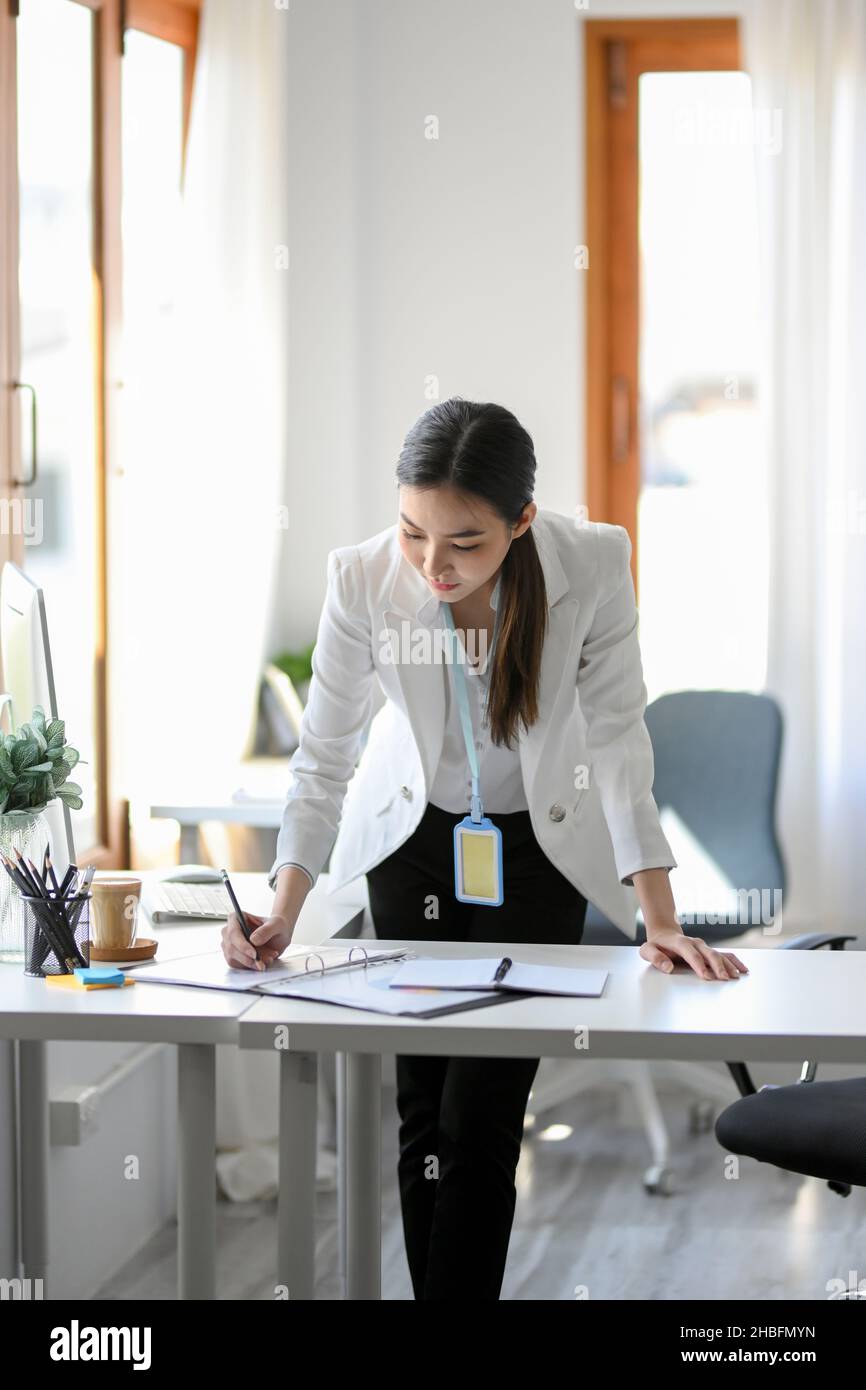 Una donna di affari riuscita e sicura è messa a fuoco sui suoi programmi di strategia finanziaria nell'ufficio. Una donna che lavora sodo progetta e analizza il marketing Foto Stock