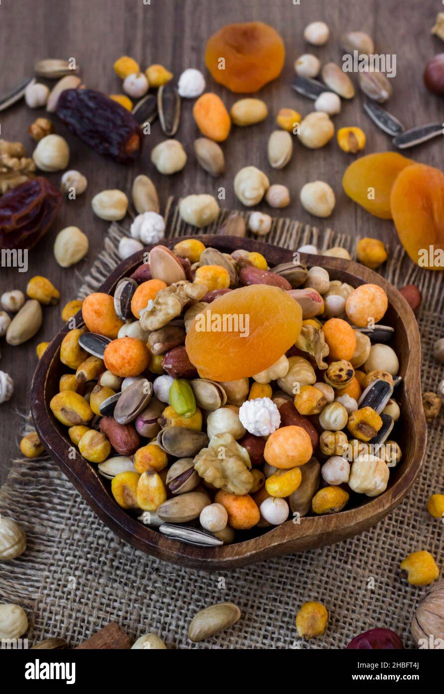 Misto, croccante, dadi secchi in un piatto di legno su tavola di legno, con frutta secca, disegno rustico, concetto di raccolto Foto Stock