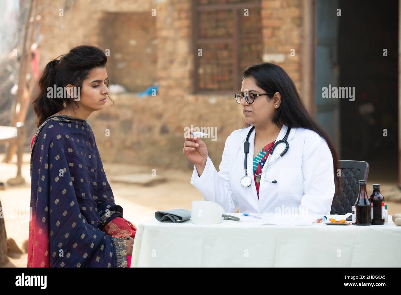 Medico indiano femmina che tiene termometro digitale controllo giovane adulto paziente ragazza al villaggio, donna che ottiene l'esame da persona medica, Rural India He Foto Stock