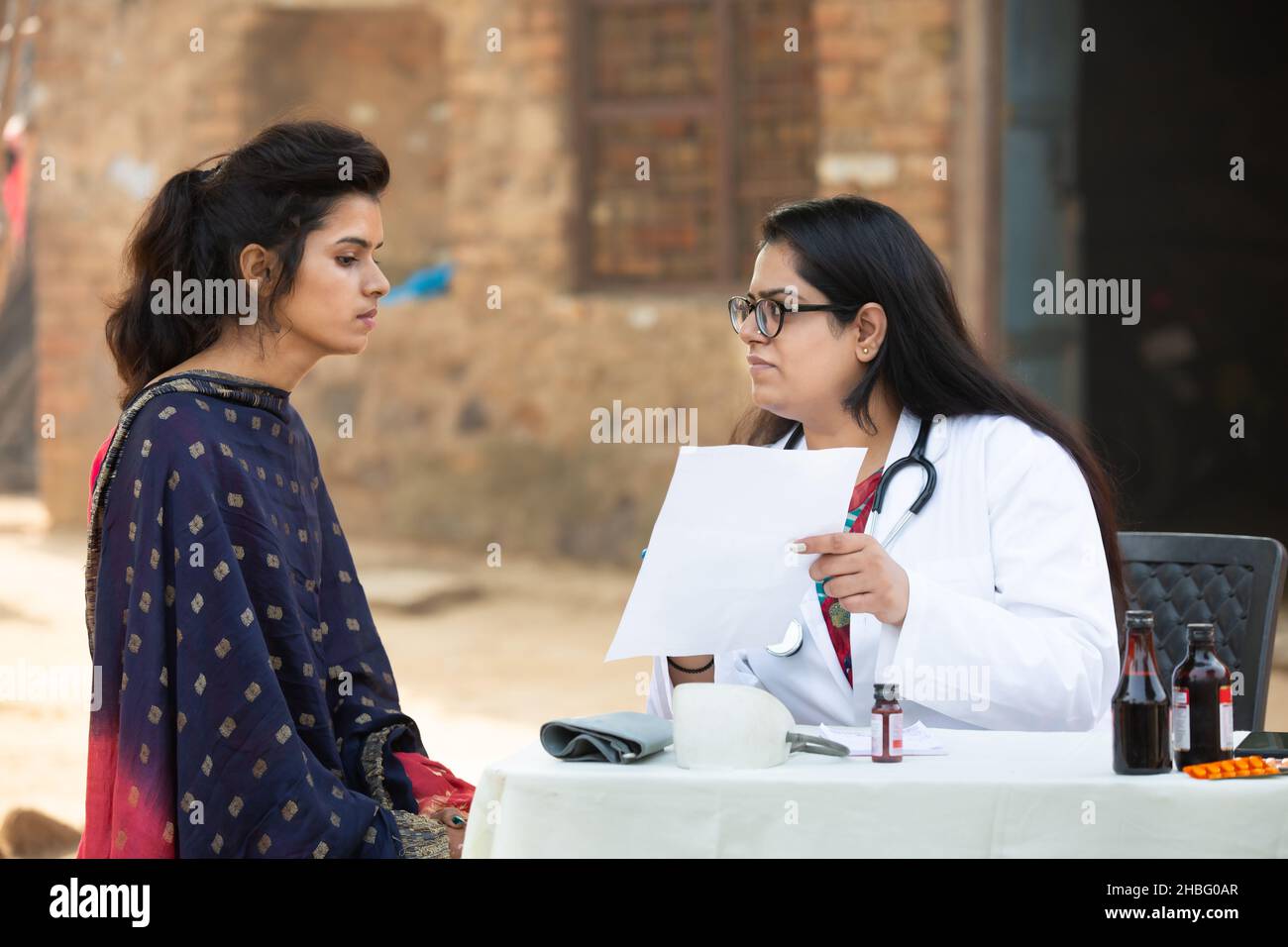 Medico femminile indiano prescrivendo medicina a giovane paziente adulto ragazza al villaggio all'aperto, donna preoccupazione che ottiene l'esame da persona medica, India rurale Foto Stock