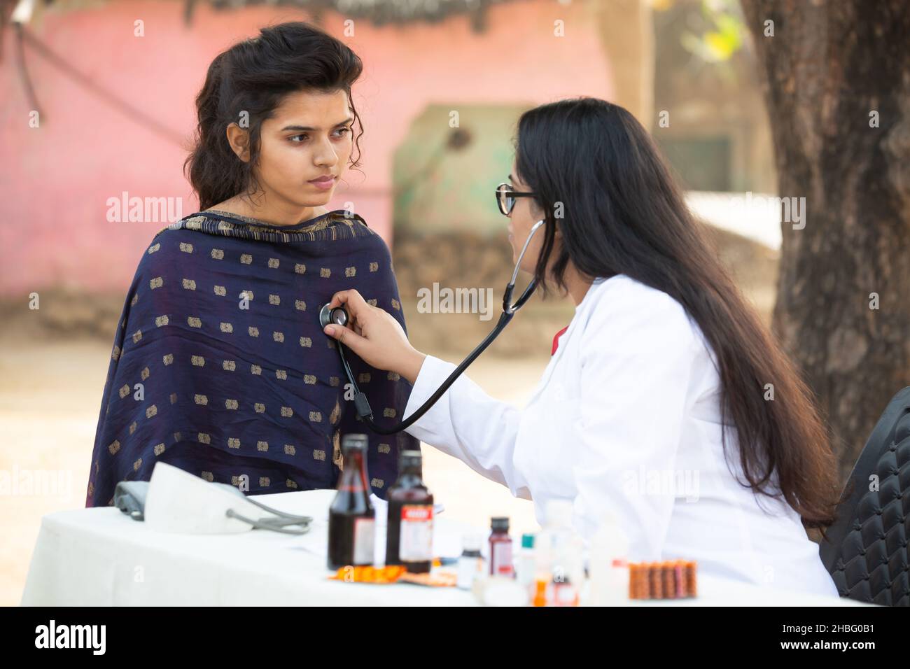 Medico indiano femmina che controlla giovane adulto ragazza paziente heartbeat con stetoscopio al villaggio all'aperto, donna che ottiene l'esame da persona medica, Rural i Foto Stock