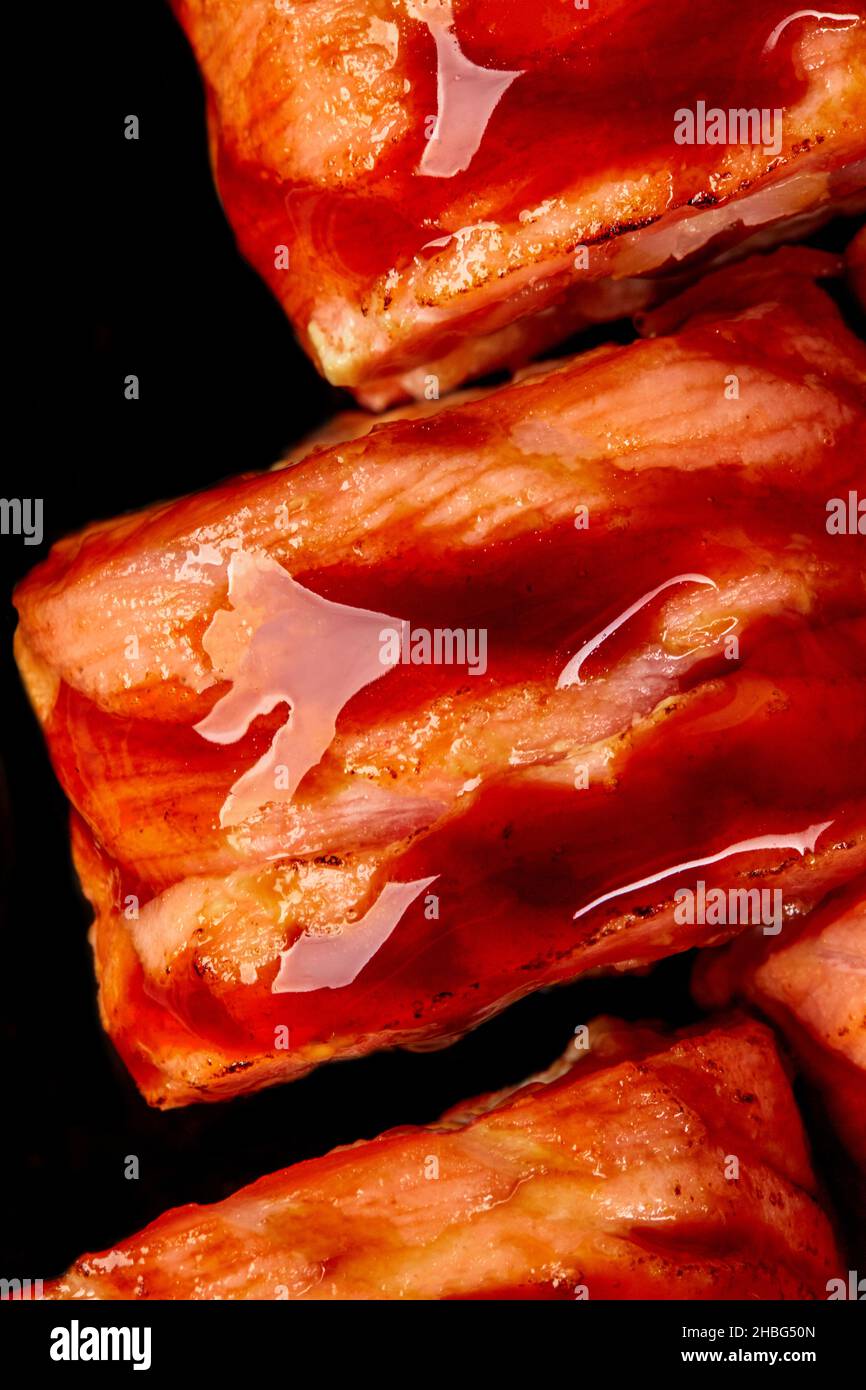 Macrosolato di sushi al salmone fritto condito con salsa unagi su sfondo nero Foto Stock