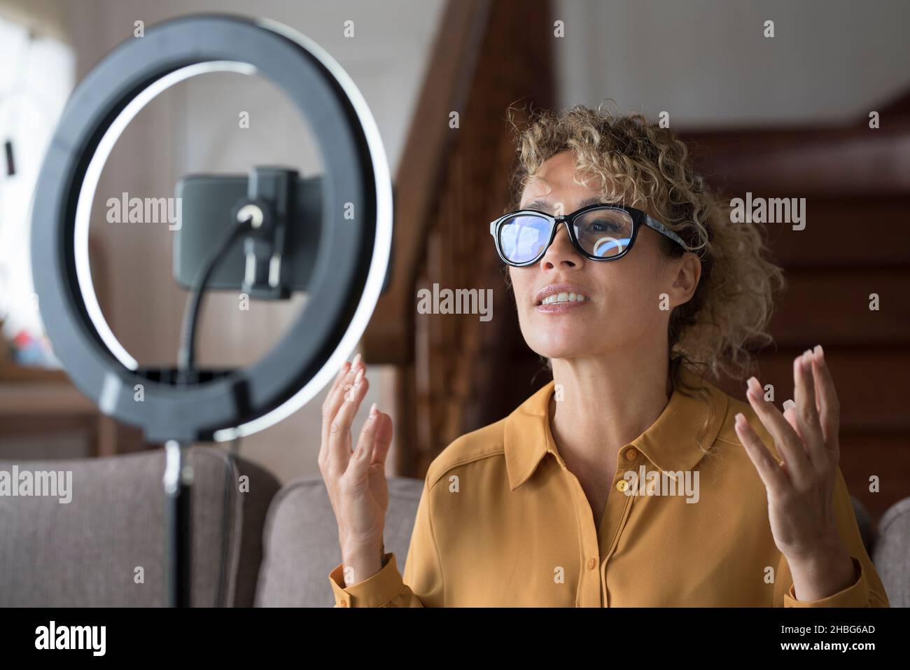 Giovane donna moderna registrare podcast dal vivo con luce ad anello e telefono cellulare da condividere on line sul tutorial web page. Business caucasi freelance di lavoro intelligente Foto Stock