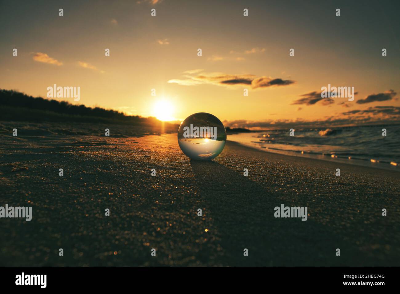 Globo di vetro sulla spiaggia del Mar Baltico in Zingst in cui è raffigurato il paesaggio. Il tramonto crea un'atmosfera calda e luminosa Foto Stock