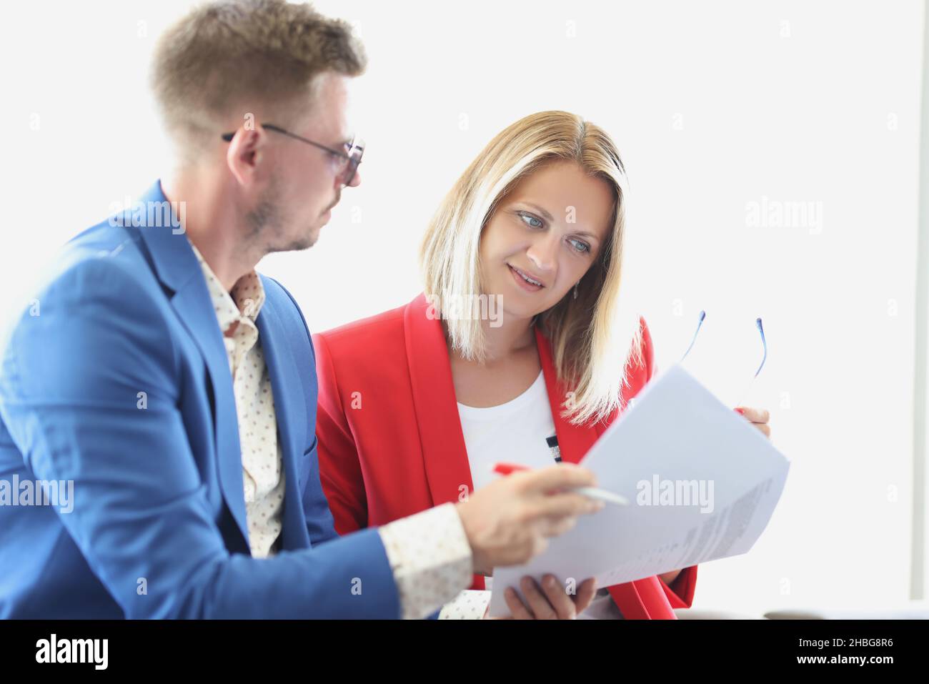 La donna concentrata passa attraverso i documenti di affari per rimuovere gli errori Foto Stock