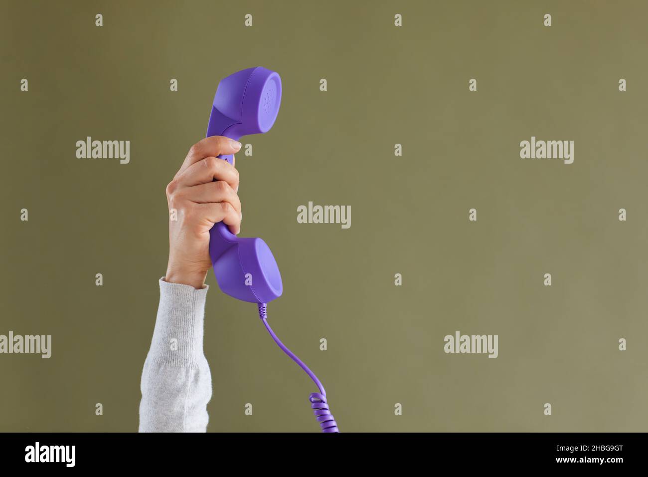 Primo piano della persona che tiene il ricevitore sullo sfondo dello studio Foto Stock