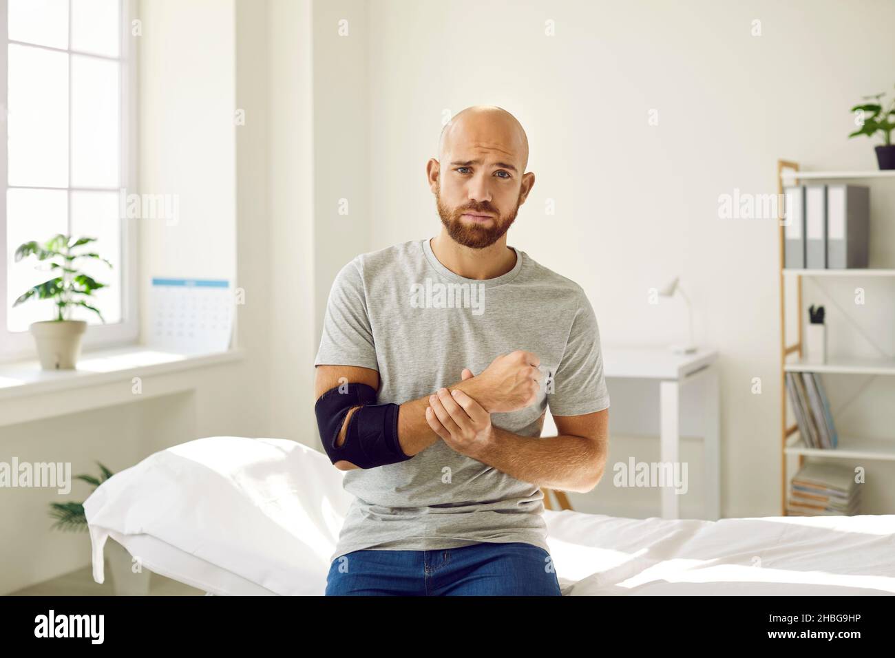 Ritratto di uomo triste che è costretto a indossare un bendaggio sul suo braccio dopo la frattura ossea. Foto Stock