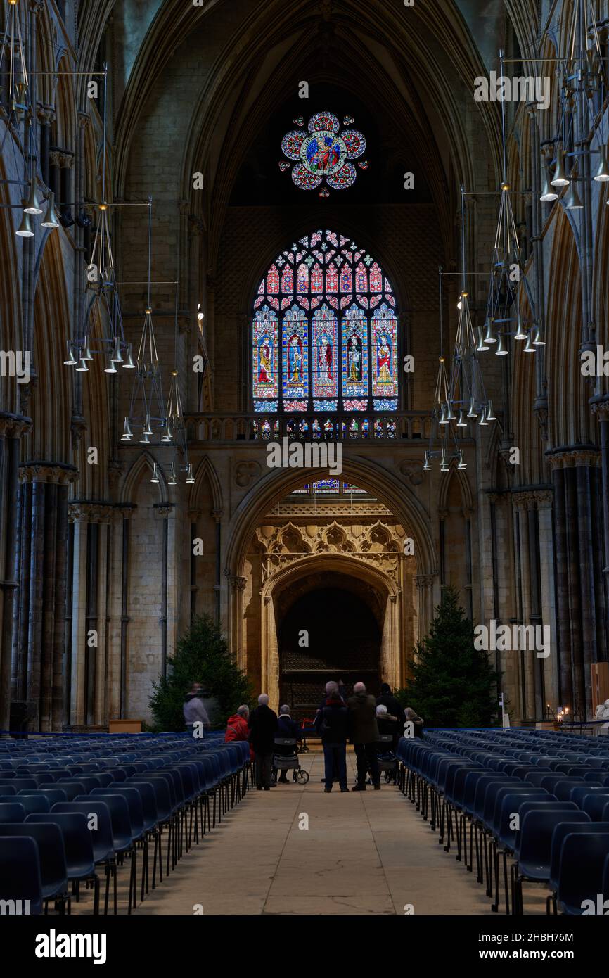 Nella navata centrale della cattedrale di Lincoln, Inghilterra, una guida e un gruppo di tour guardano le finestre di vetro colorate del West End. Foto Stock
