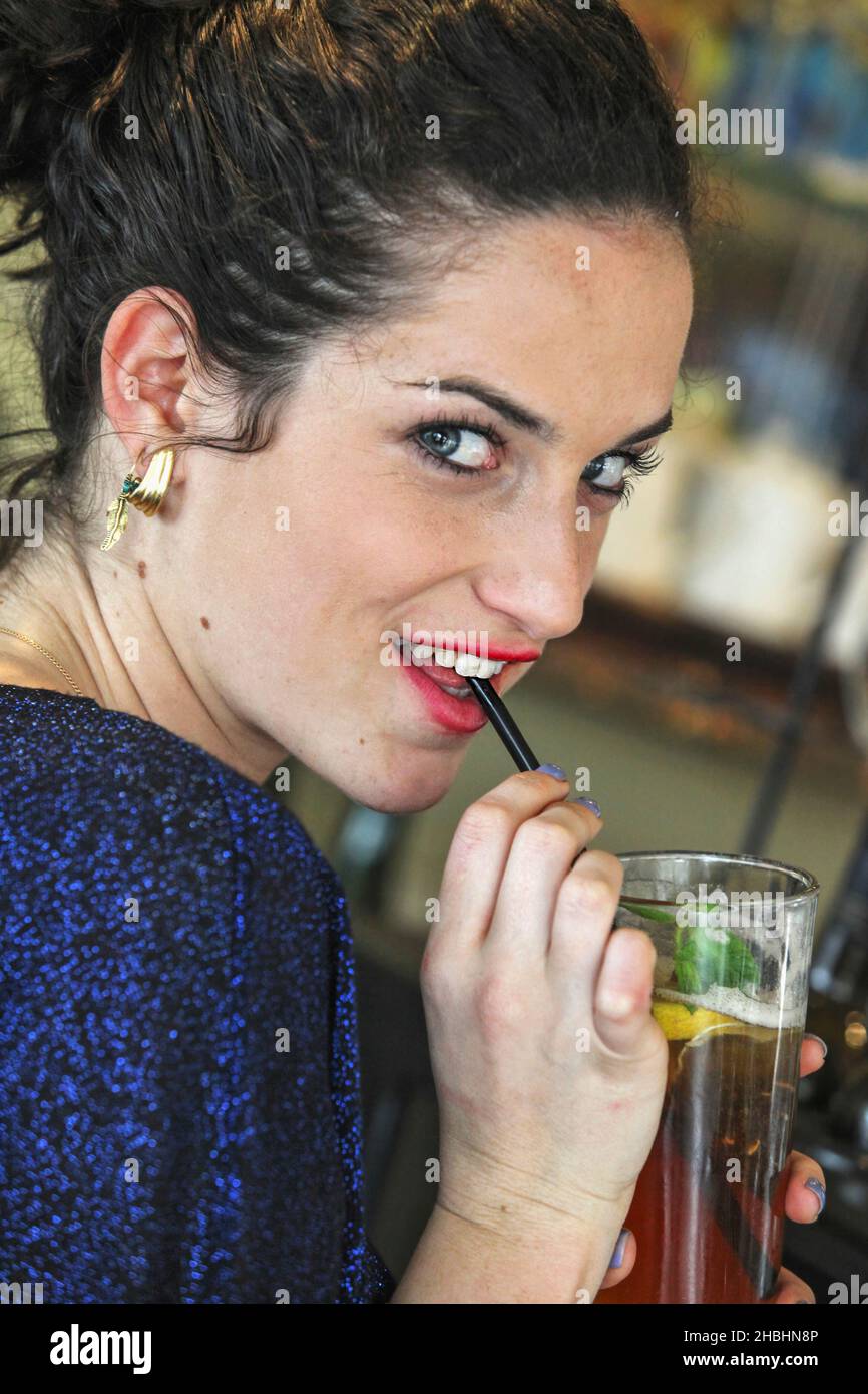 La giovane donna beve tè ghiacciato con una paglia Foto Stock