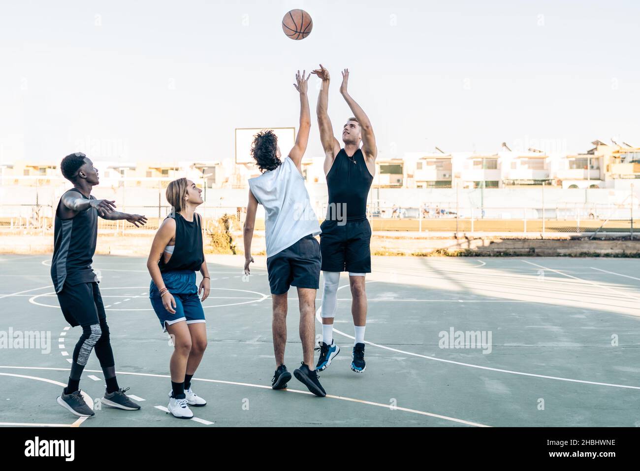 Gruppo di amici che giocano a basket in un campo all'aperto Foto Stock