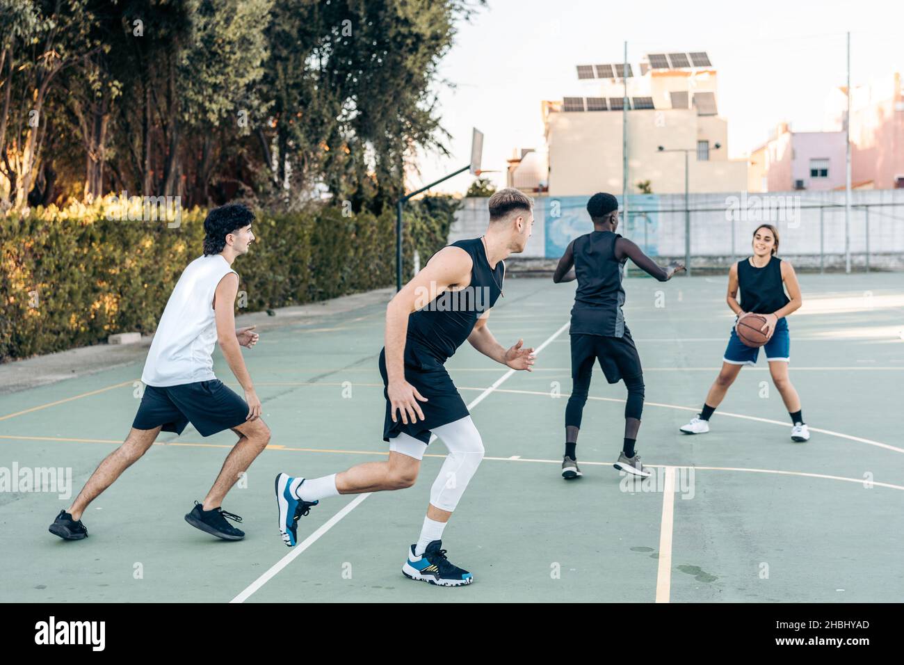 Quattro amici multiculturali che giocano a basket all'aperto Foto Stock