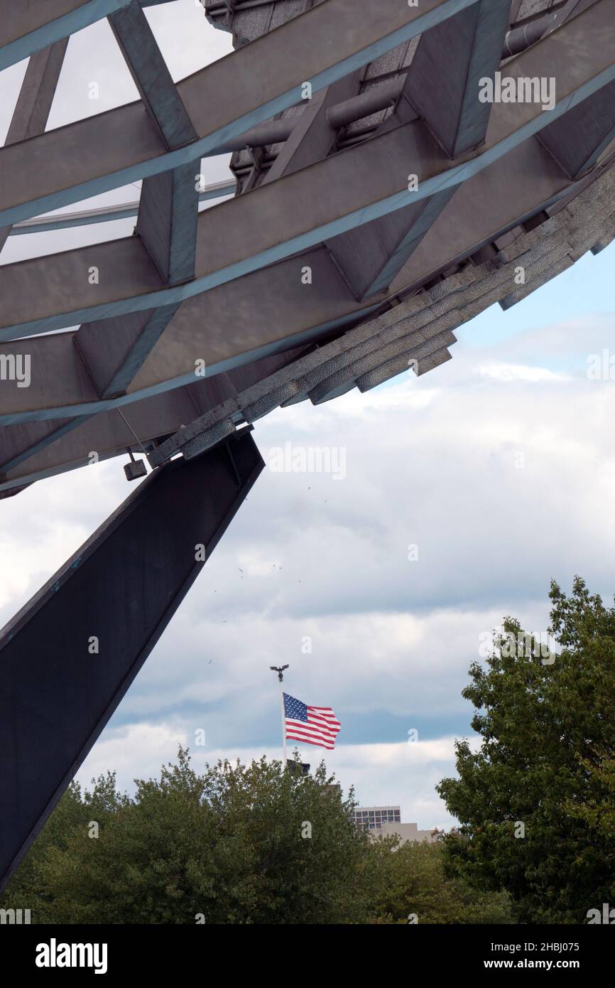 La bandiera americana vista da dietro l'Unisphere nel parco di Flushing Meadows Corona nel Queens New York City. Foto Stock