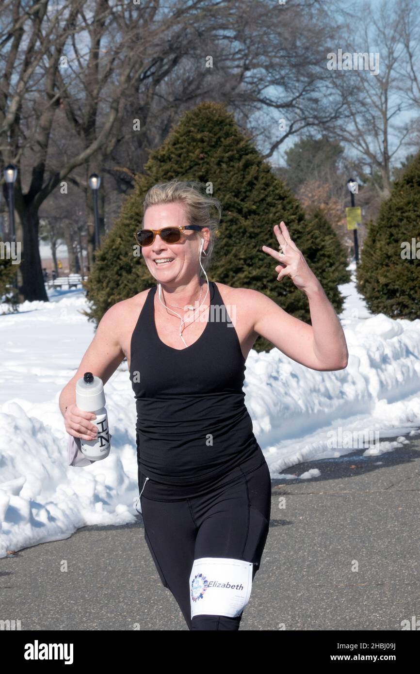 Una donna runner, che conclude la corsa di 4 miglia del Winter Park Tour di NYC a Flushing Meadows Corona Park a Queens, New York. Foto Stock