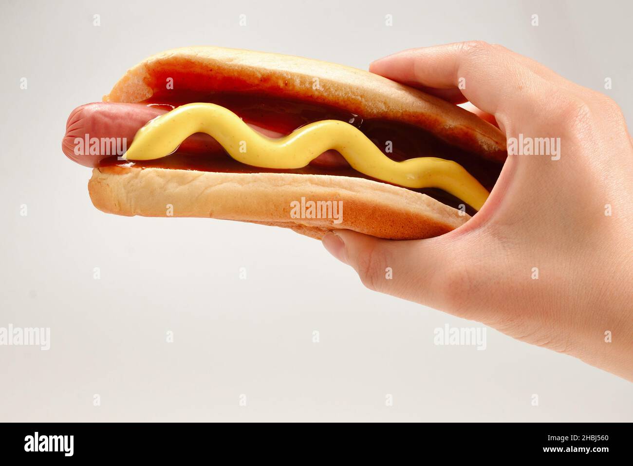 Hot dog in mano donna isolato su sfondo bianco. Spazio di copia. Foto Stock