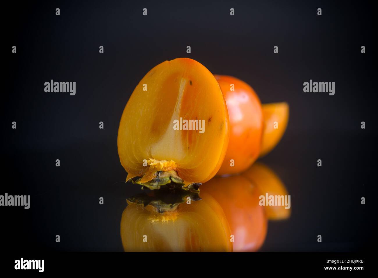 mezzo persimmon tagliato maturo isolato su nero Foto Stock