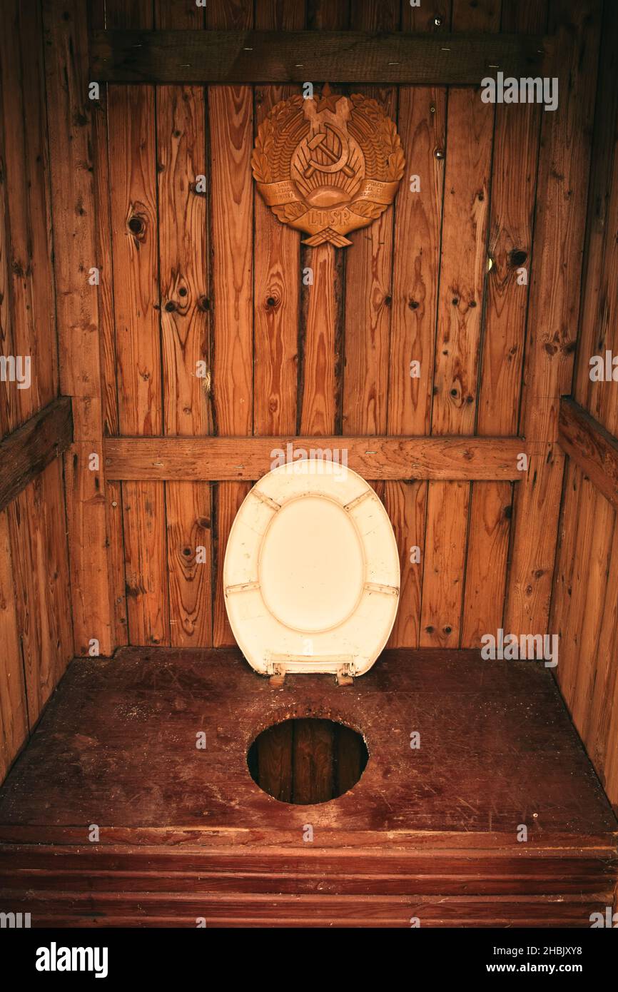 Lituania - 15 giugno 2021: Interno cabina toilette in legno con coperchio bianco e cartello propagandistico sopra. Foto Stock