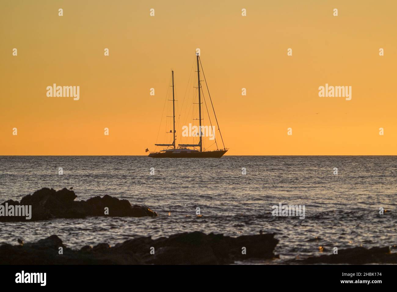 Barca a vela al tramonto vela di fronte alla costa, Andalusia, Spagna. Foto Stock