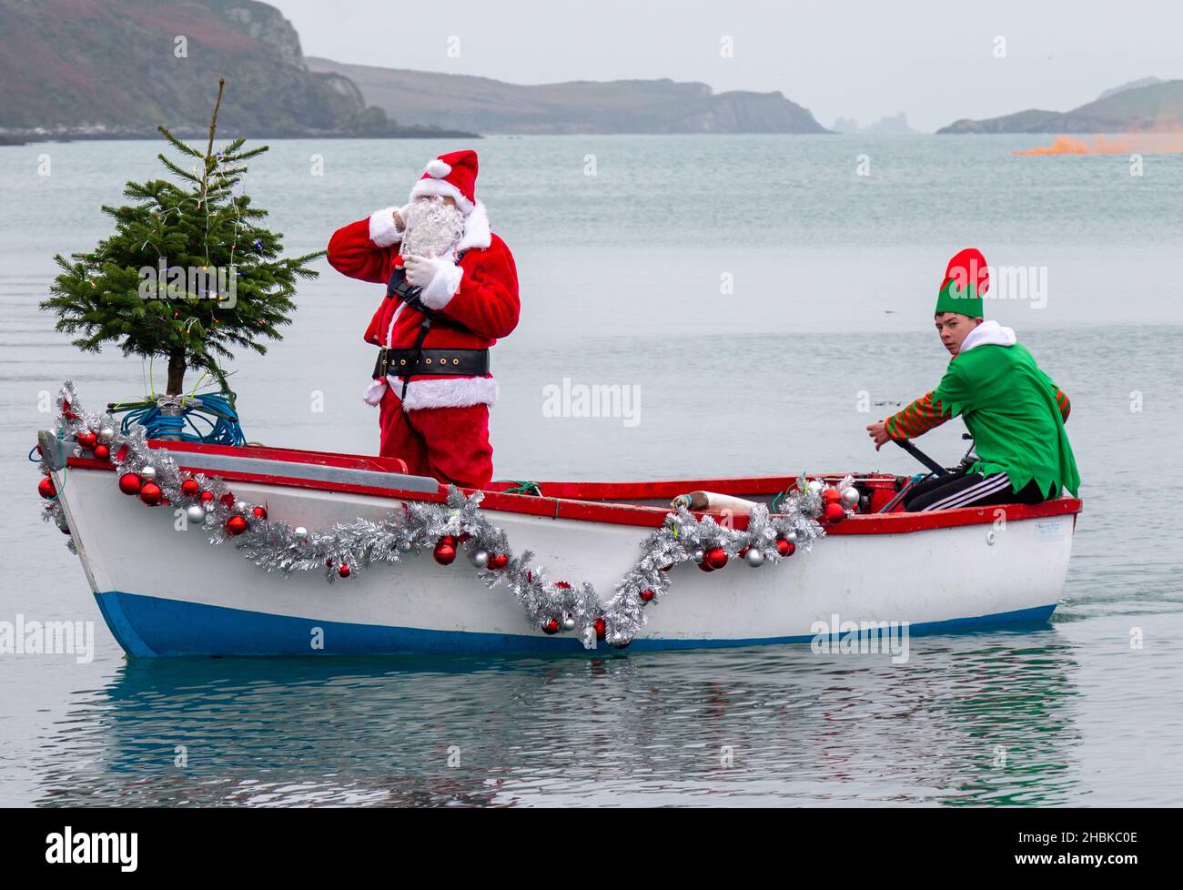 Babbo Natale o Babbo Natale che arriva in barca con il suo Elf alla guida Foto Stock