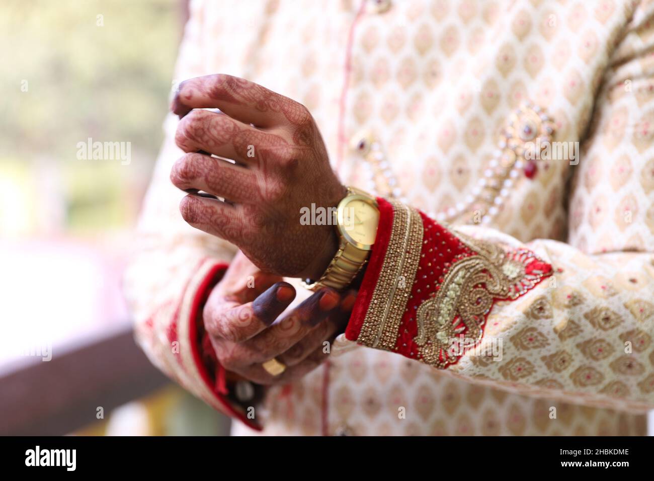 Primo piano della mano dello sposo indiano che indossa sherwani intrecciati e un orologio sulla mano durante la cerimonia nuziale Foto Stock Primo piano della mano dello sposo indiano che indossa sherwani intrecciati e un orologio sulla mano durante la cerimonia nuziale Foto Stock