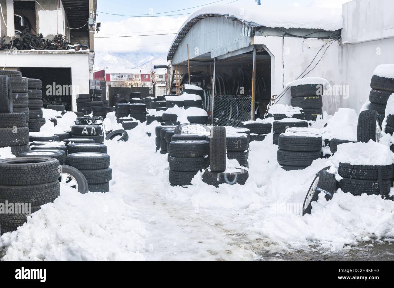 Mucchi di pneumatici sotto la neve in fusione in una giornata di primavera con stop in primo piano. Concetto di sostituzione stagionale degli pneumatici. Foto Stock