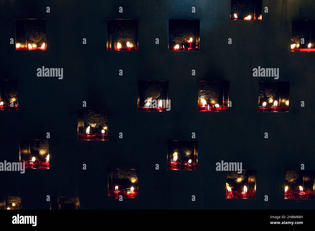 Parete scura con candele brucianti . Lume di candela nella stanza nera Foto Stock