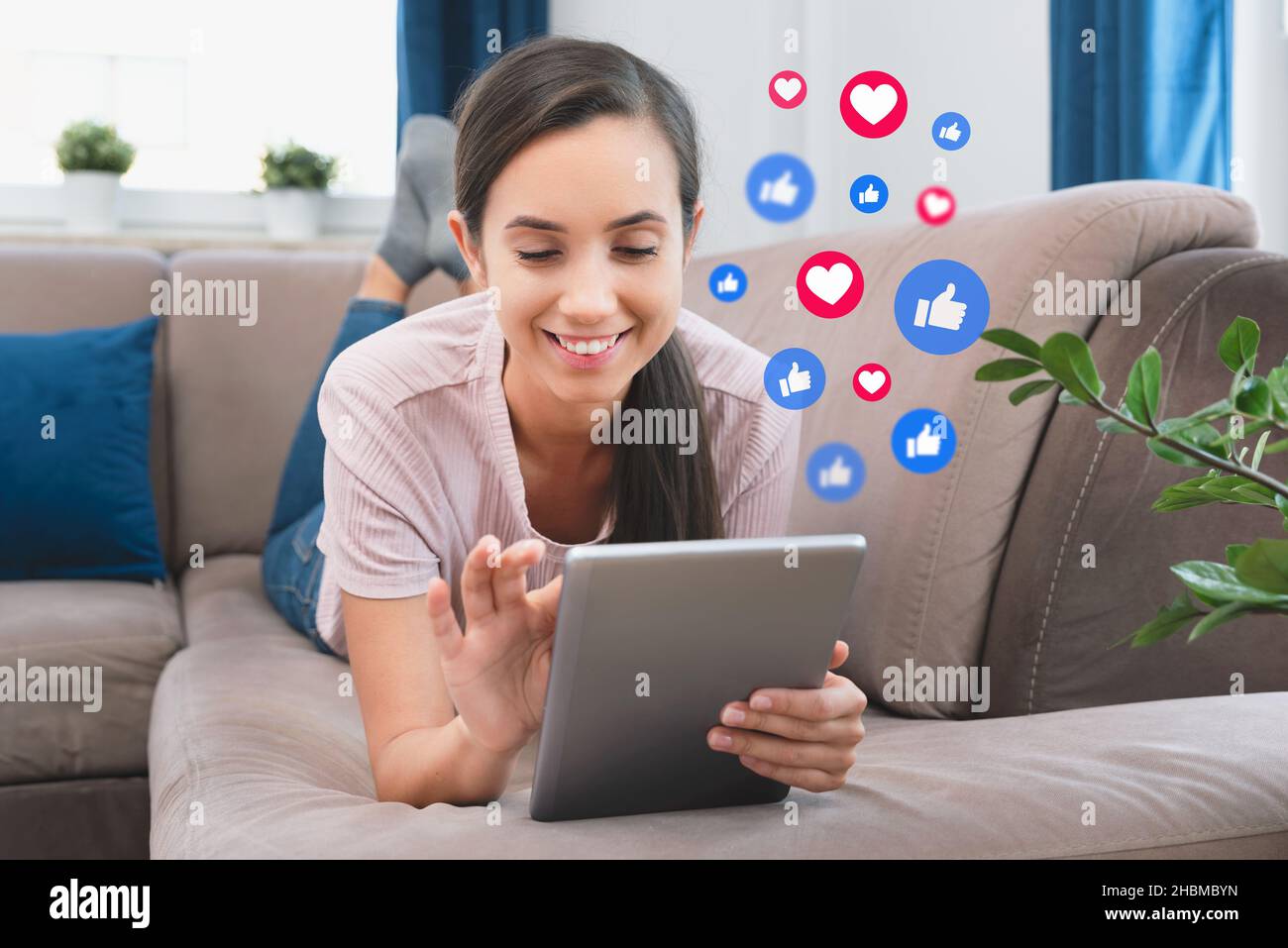 Giovane donna che usa i social media. Icone che volano dal tablet digitale Foto Stock