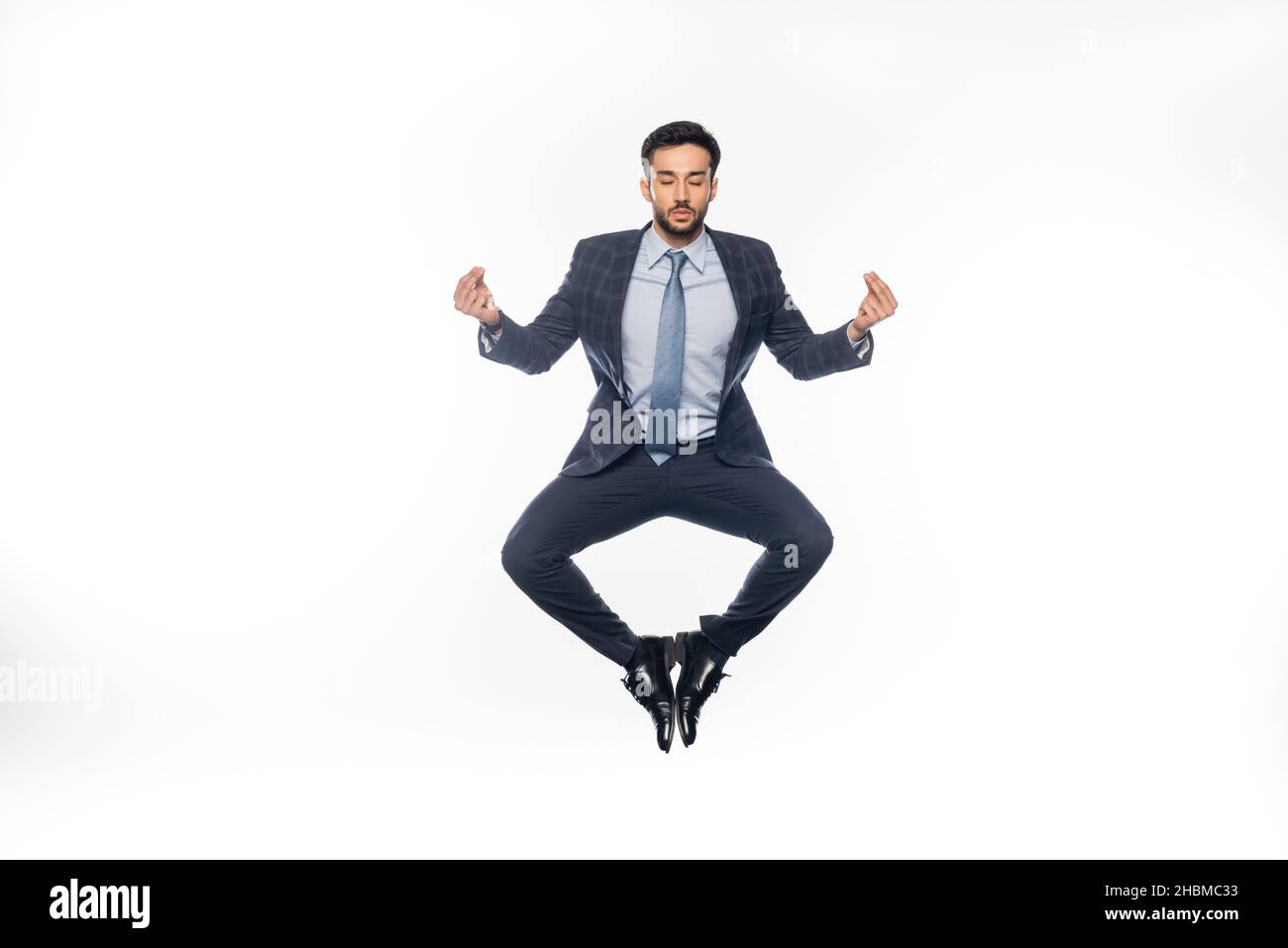 uomo d'affari in vestito levitating e meditating sul bianco Foto Stock