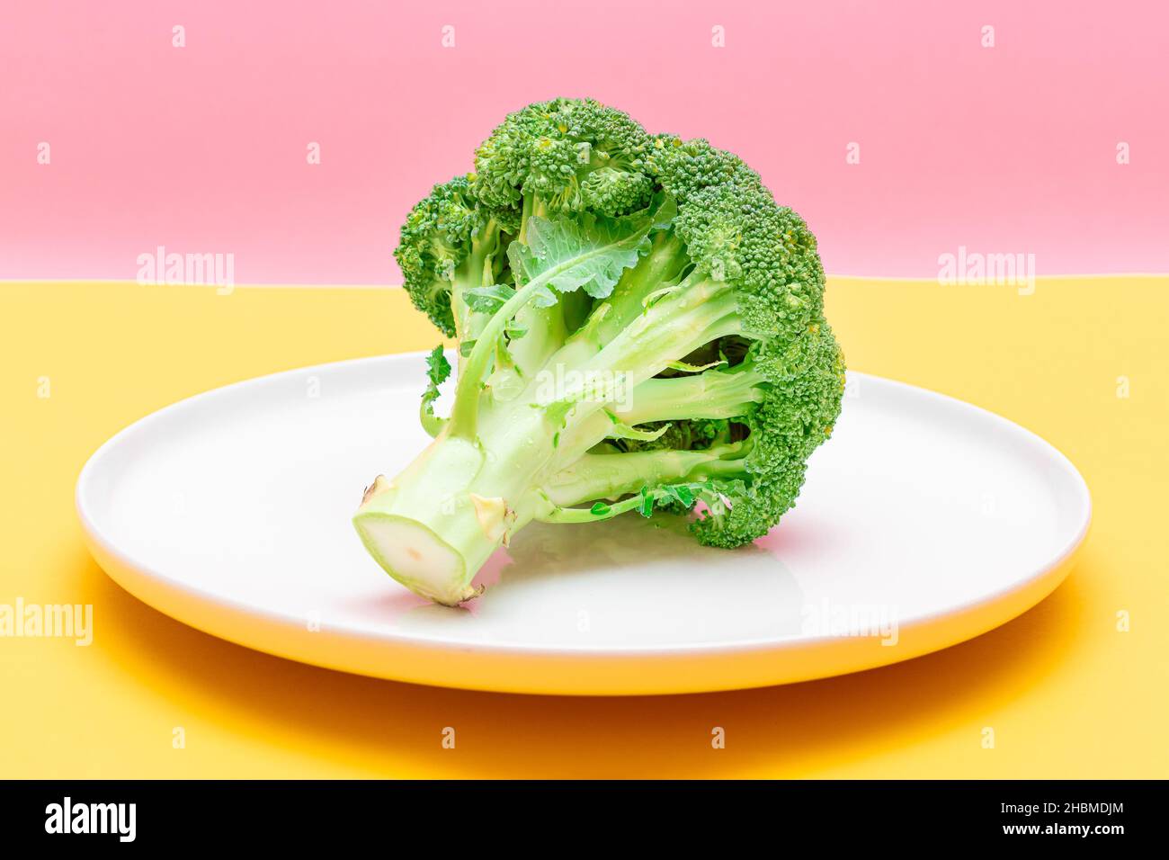Broccoli freschi e crudi su piatto bianco. Cavolo verde non fatto. Cultura vegana e vegetariana. Cibo crudo. Alimentazione sana e dieta vegetale Foto Stock